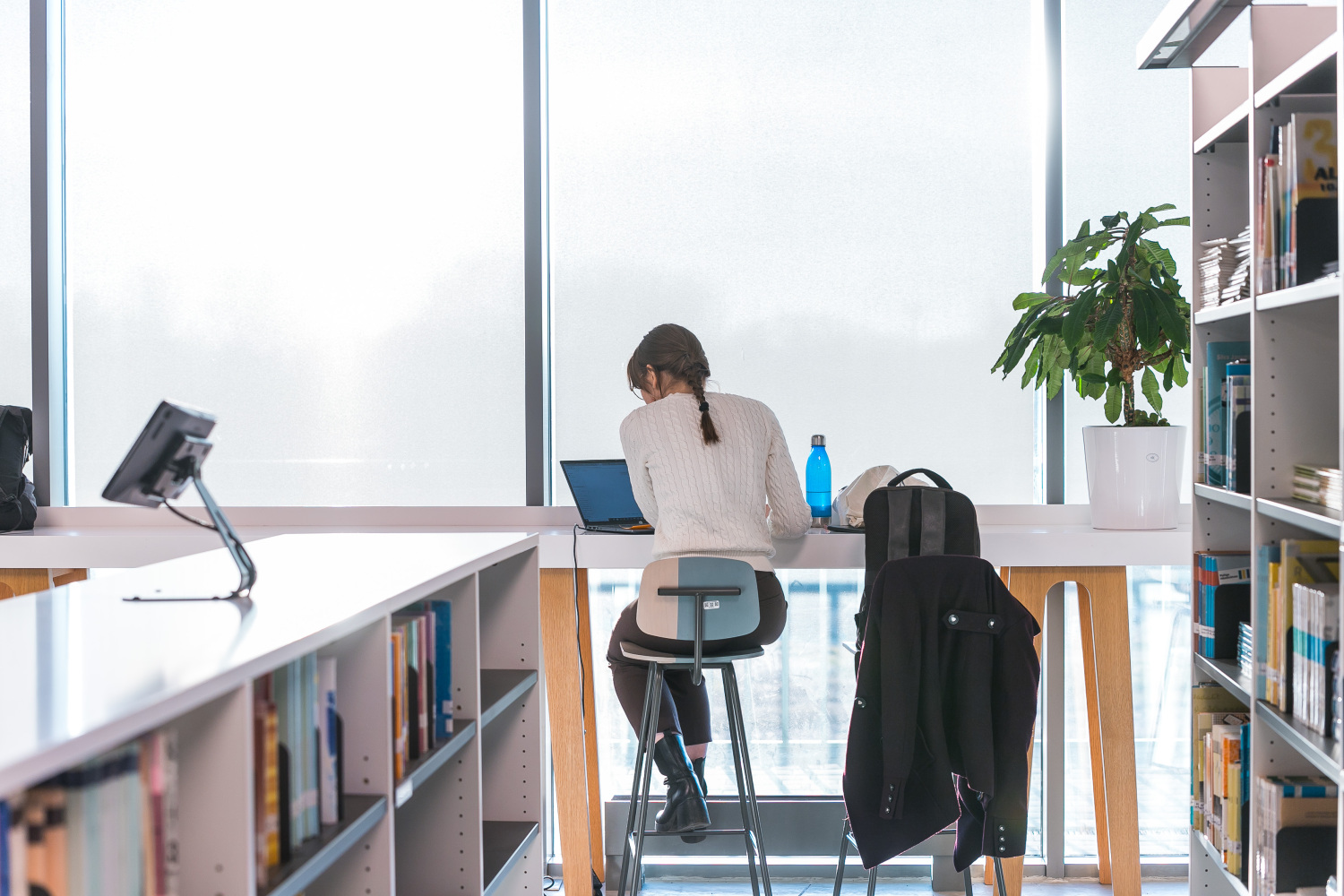 The student is studying at the table in the library