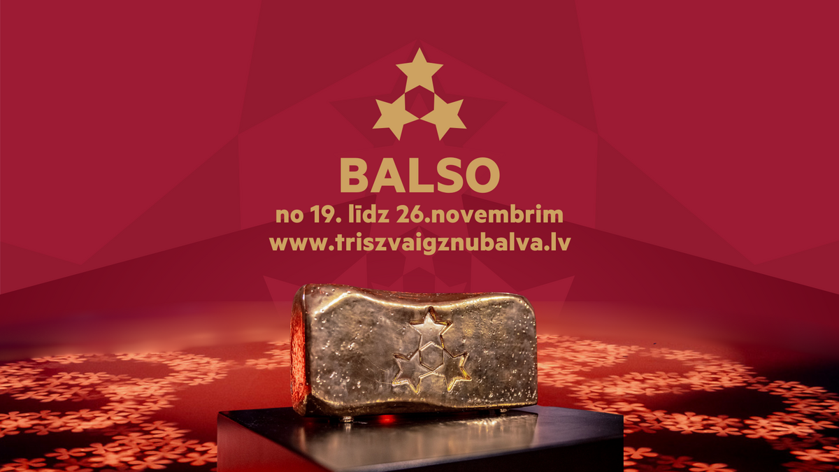 Zelta Trīs Zvaigžņu balvas statuja uz tumša pjedestāla, fonā sarkans dizains ar trīs zvaigznēm un tekstu “BALSO no 19. līdz 26. novembrim www.triszvaigznubalva.lv