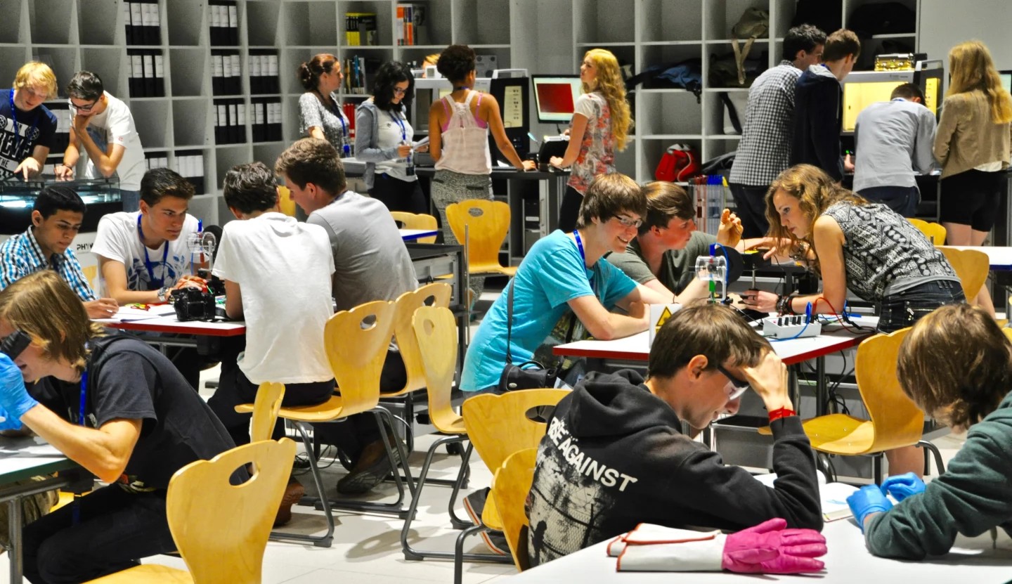 Jaunieši sēž telpā pie galdiem