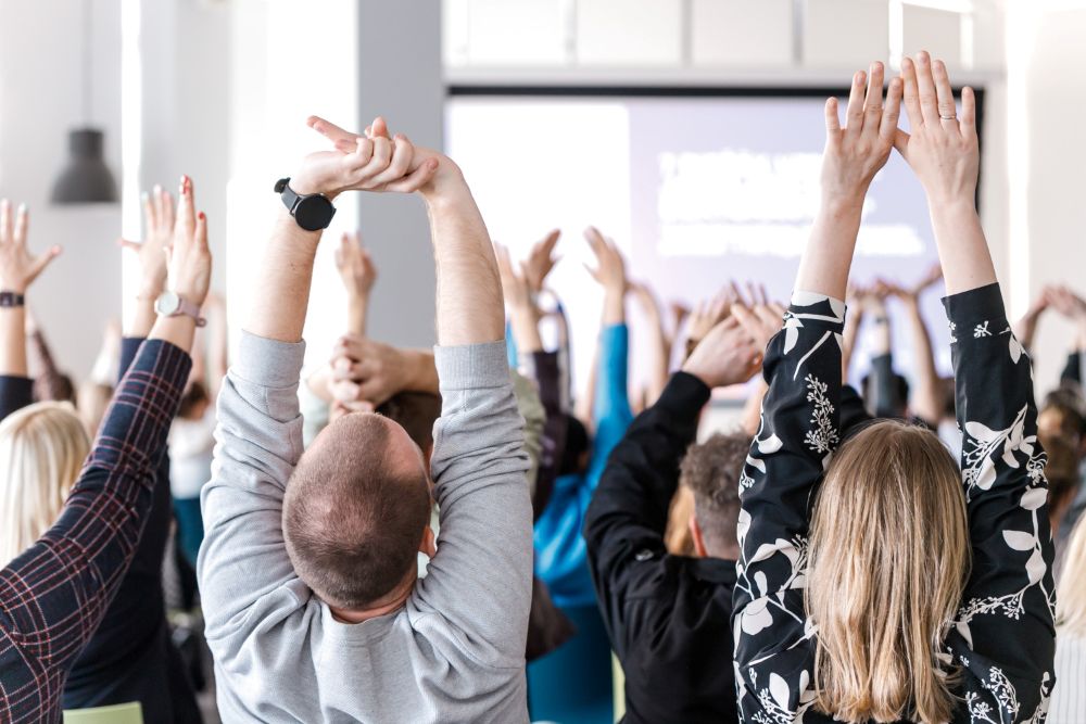 Studenti lekciju telpā kopīgi izstiepj rokas augšup