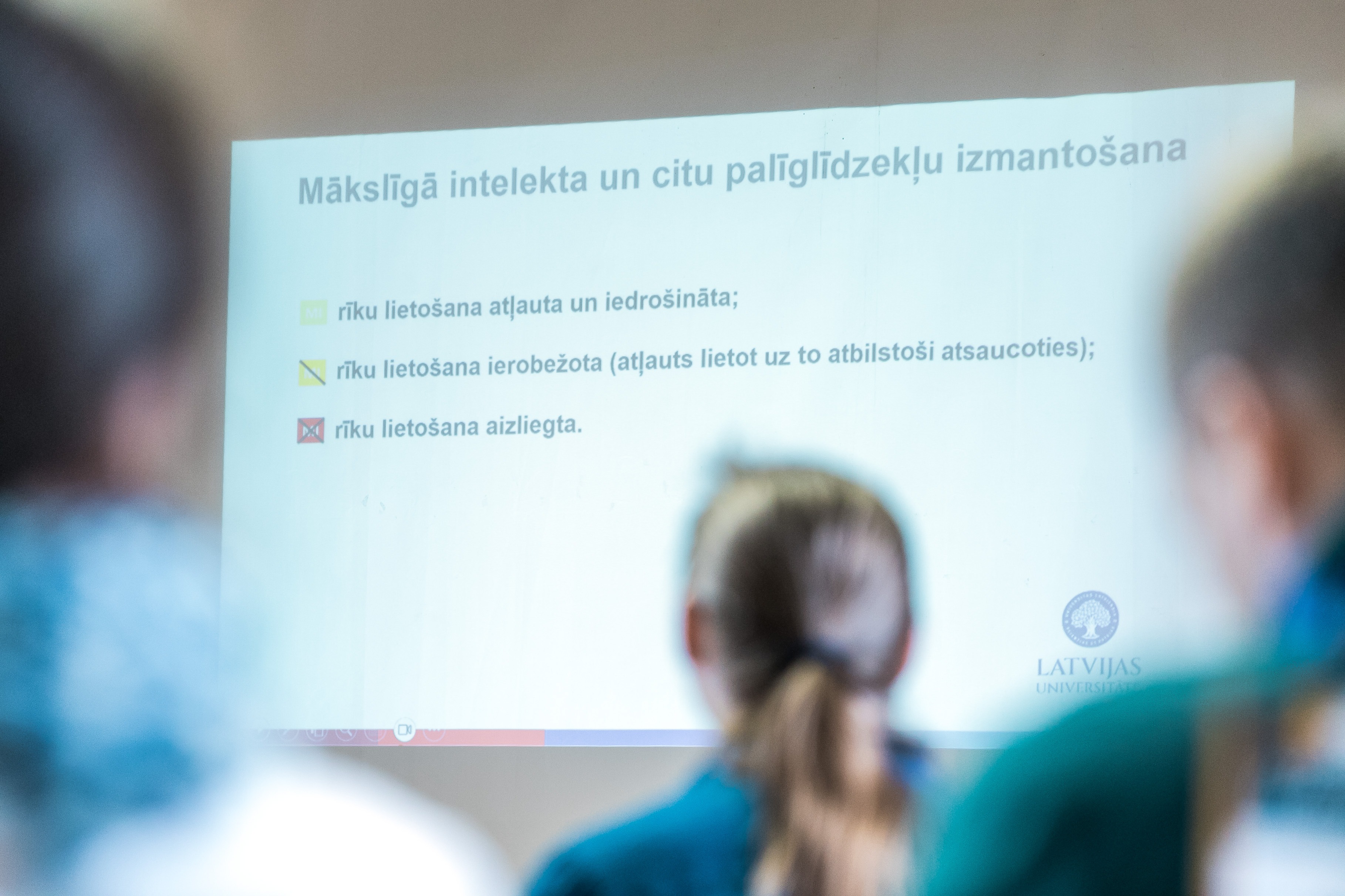 Jaunieši skatās prezentācijas slaidu par mākslīgā intetelekta izmantošanu