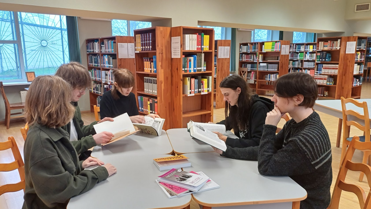 Vēstures studenti bibliotēkā pie galda