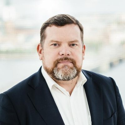 Vīrieša portretfoto zilā uzvalkā un gaišā kreklāю