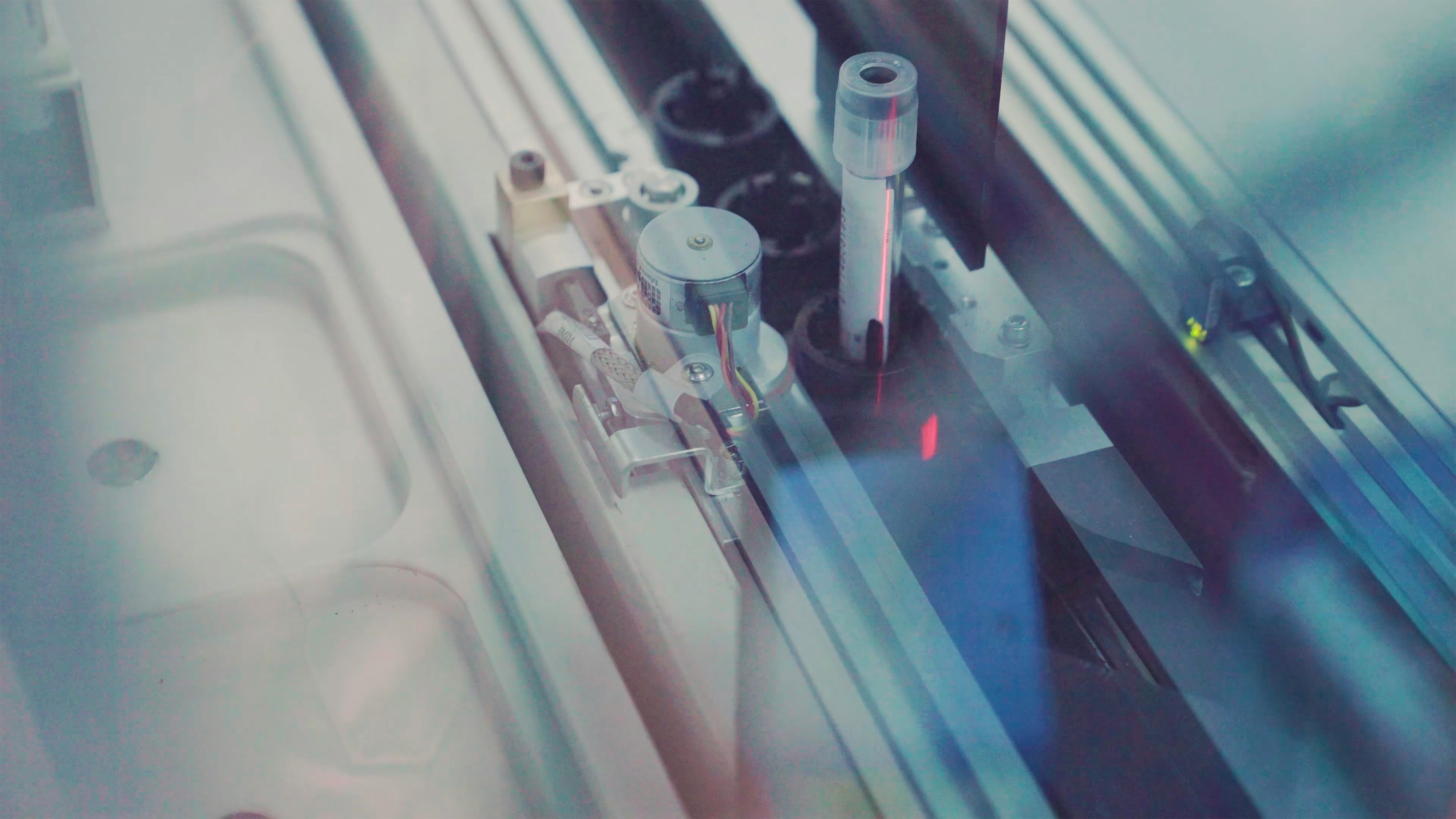 Close-up of laboratory equipment with test tubes and a red laser light — scientific research apparatus.