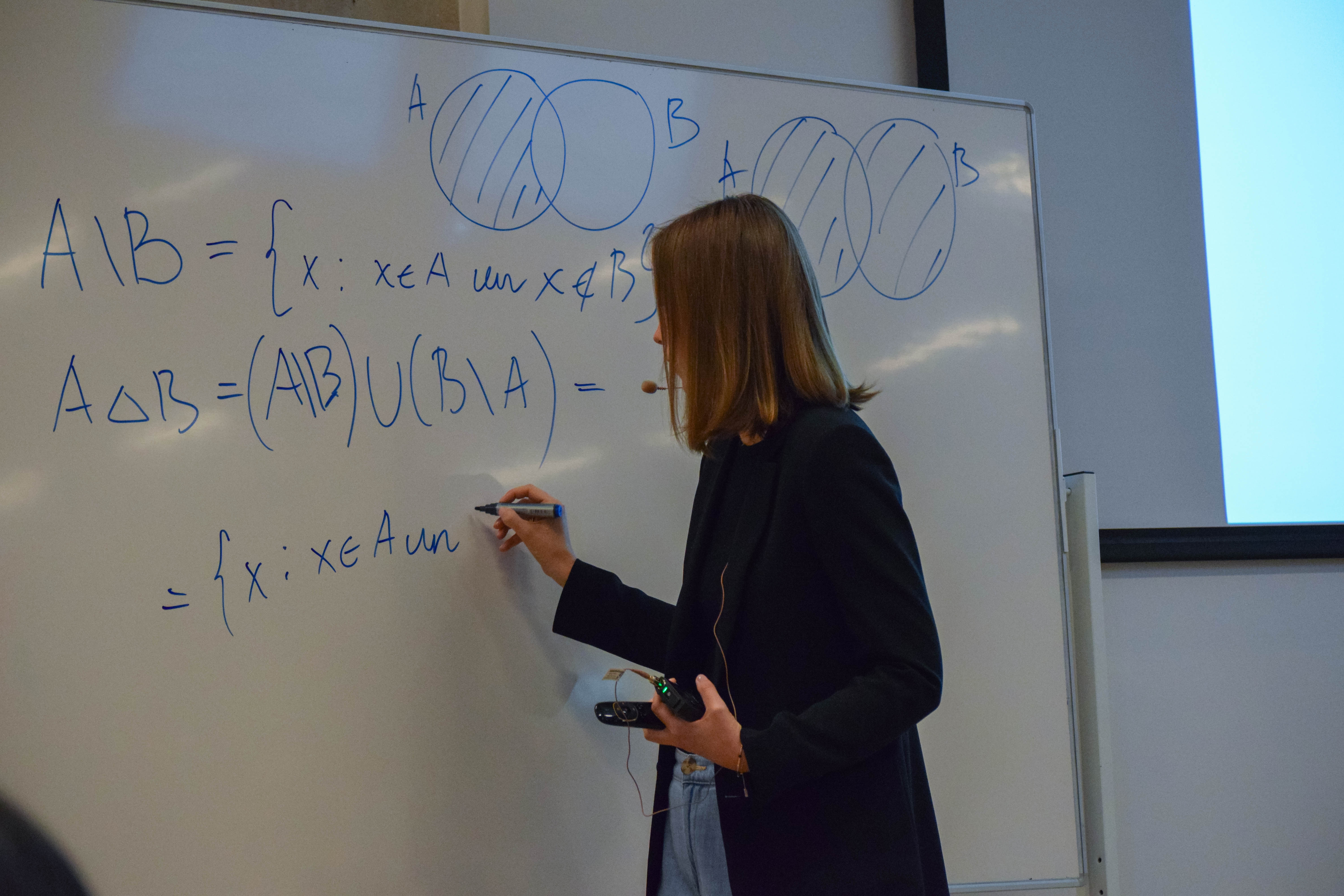 Sieviete raksta uz baltās tāfeles ar zilu flomasteri