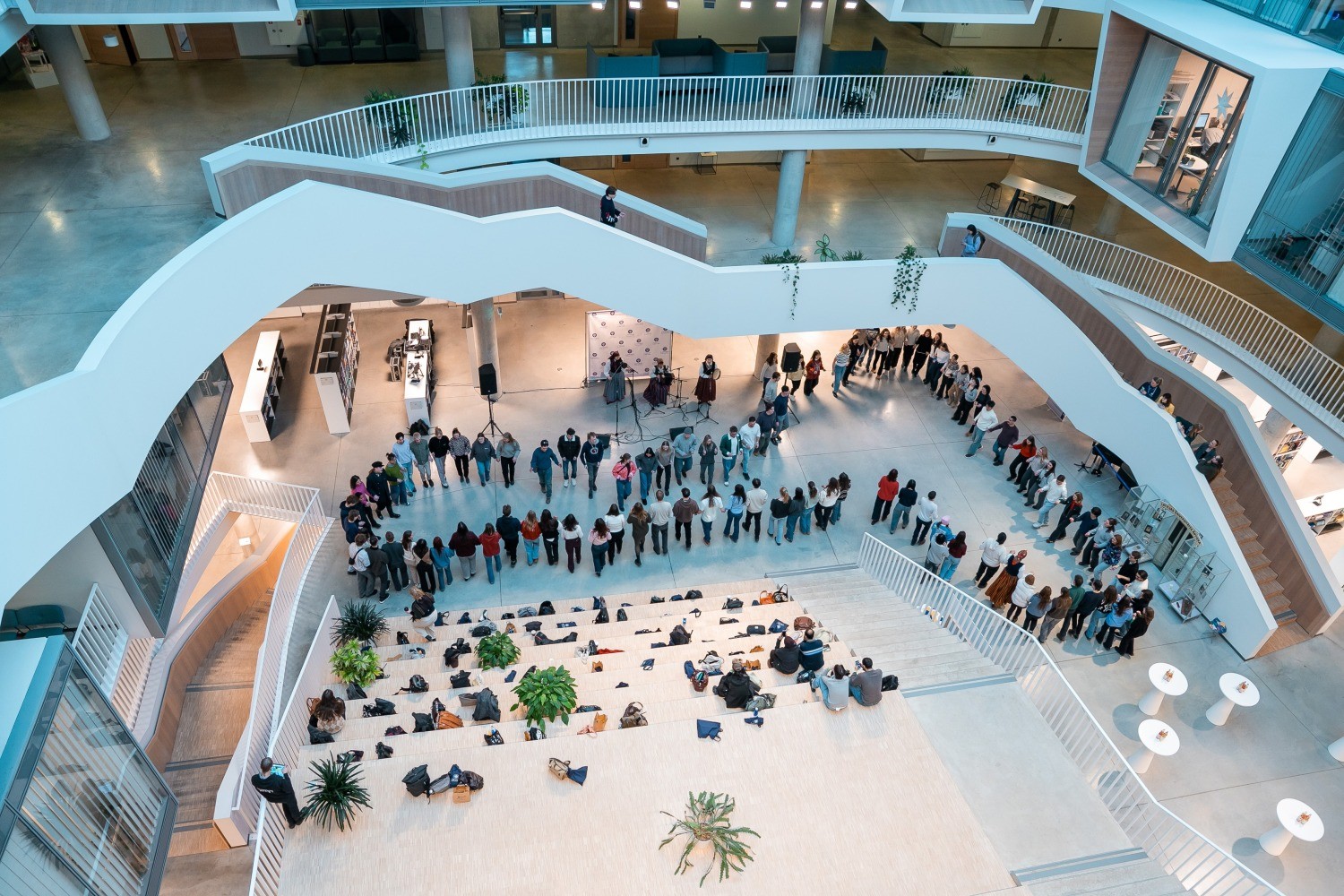 Studenti pulcējušies aplī Latvijas Universitātes Akadēmiskā centra ātrijā.