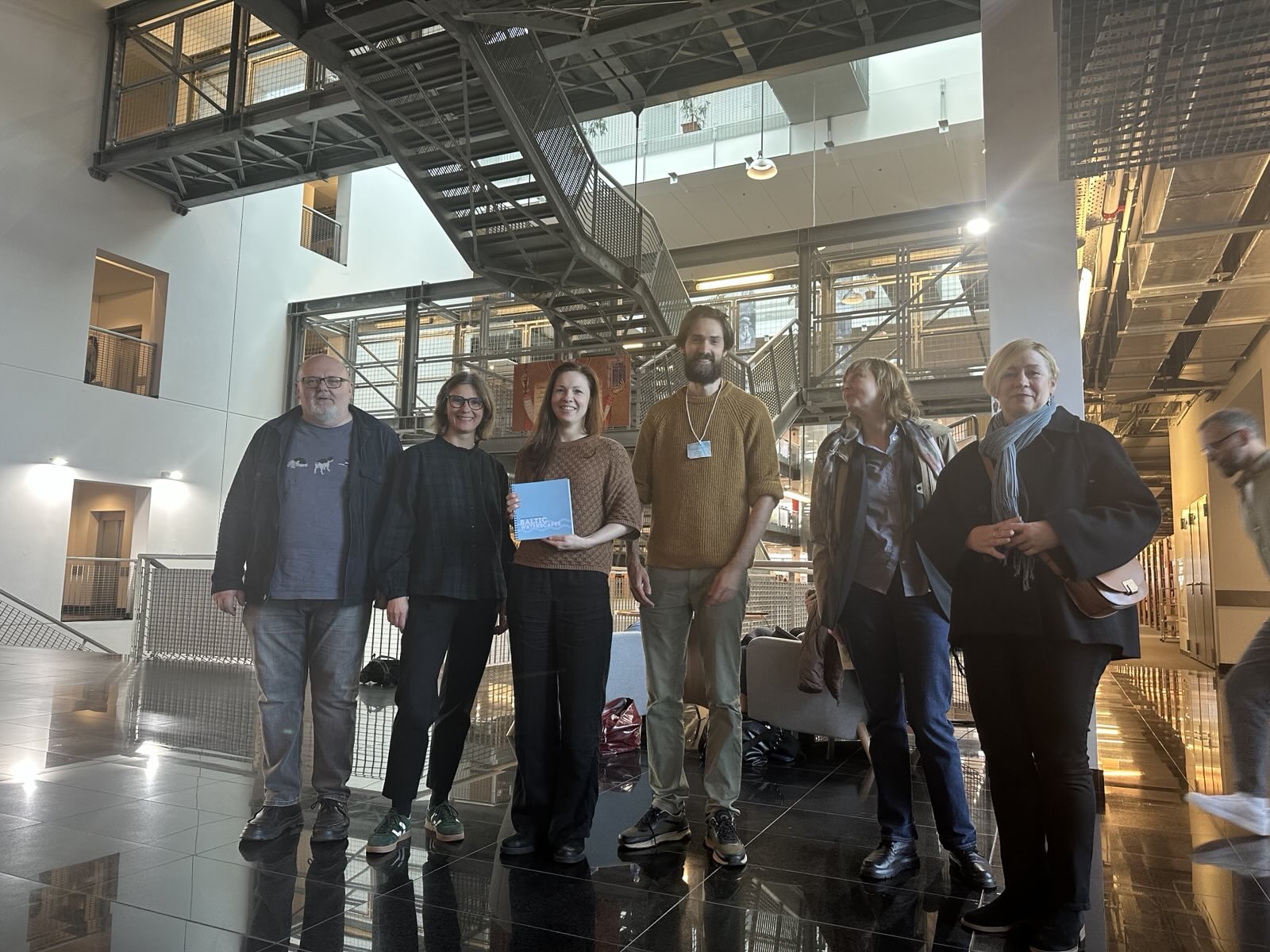 The photo shows the project researchers (from left) Artis Svece, Anita Zariņa, Kristīne Krumberga, and Kālis Lakševics. On the right are two conference participants.