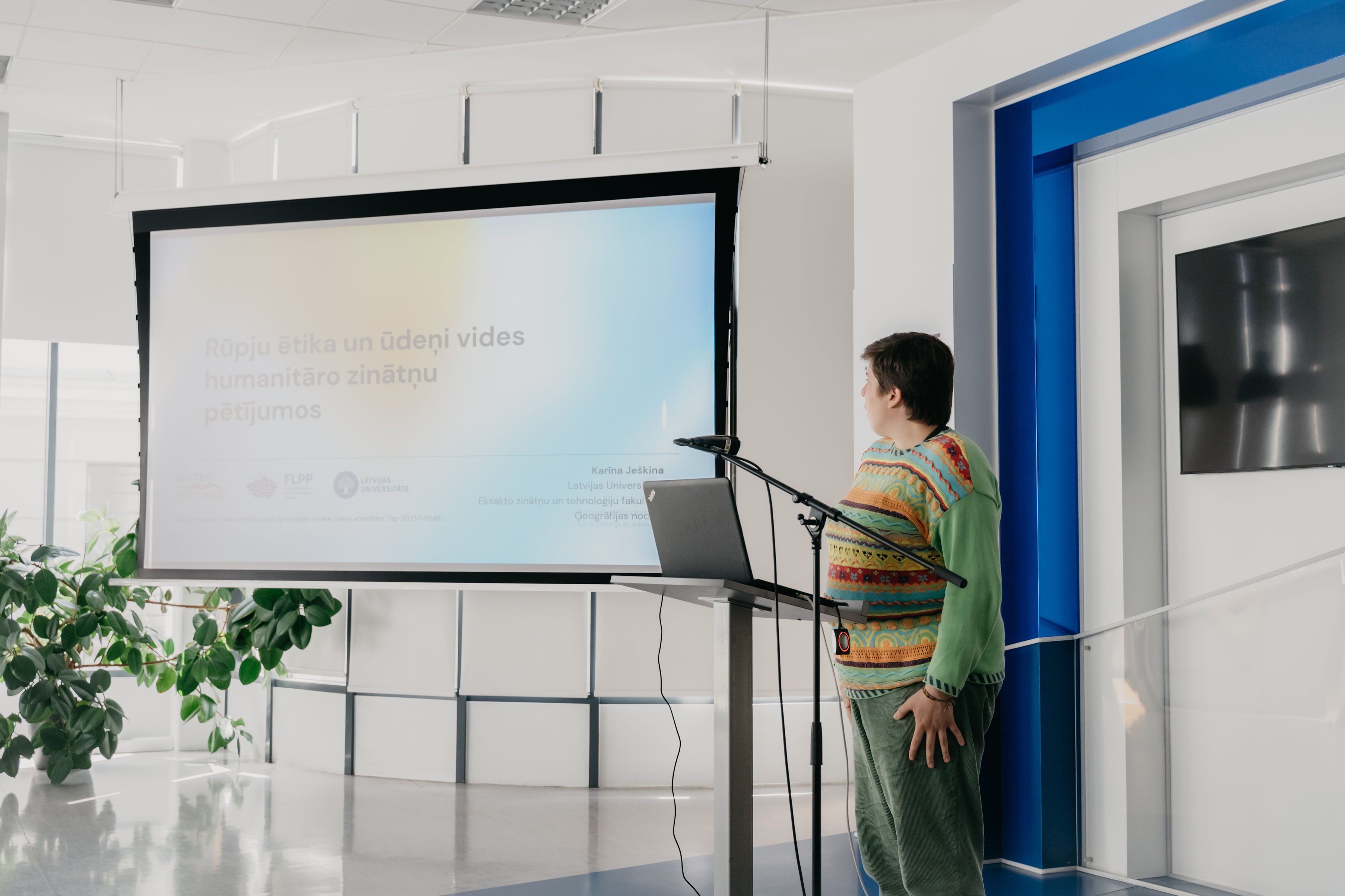 On the right side of the image is the author of the presentation, Karīna Ješkina. In the center and on the left is the presentation screen with the title slide and the inscription "Ethics of Care and Water in Environmental Humanities."